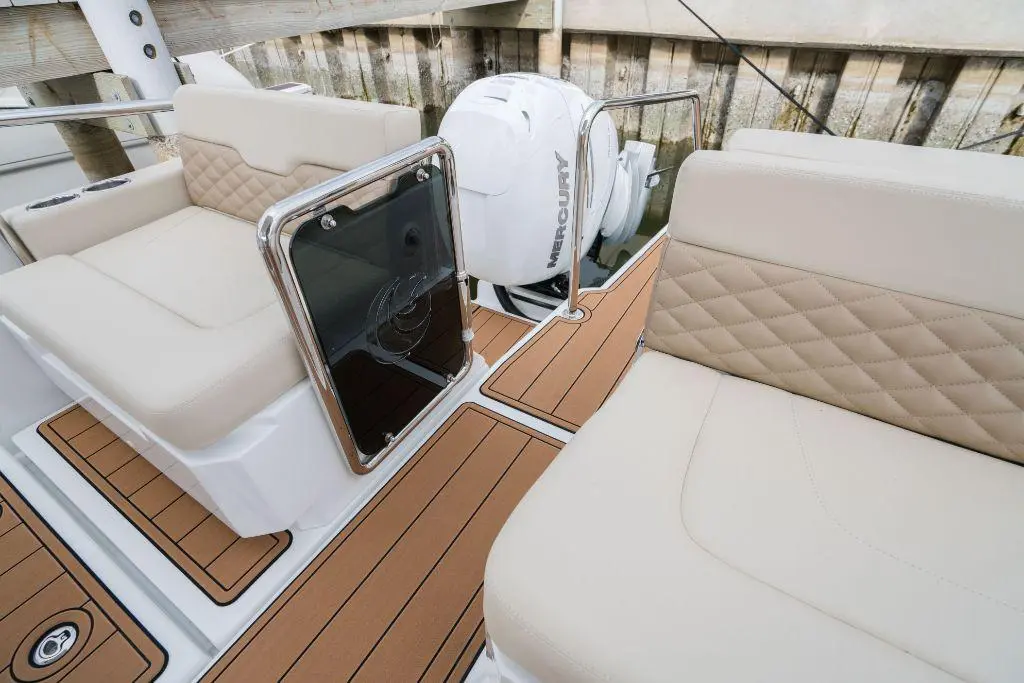 Interior view of a modern boat featuring beige cushioned seats, a polished surface, and a visible Mercury outboard motor.